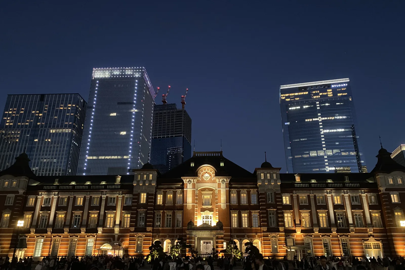 Tokyo Station's illuminated red-brick Marunouchi facade framed by modern office towers at night
